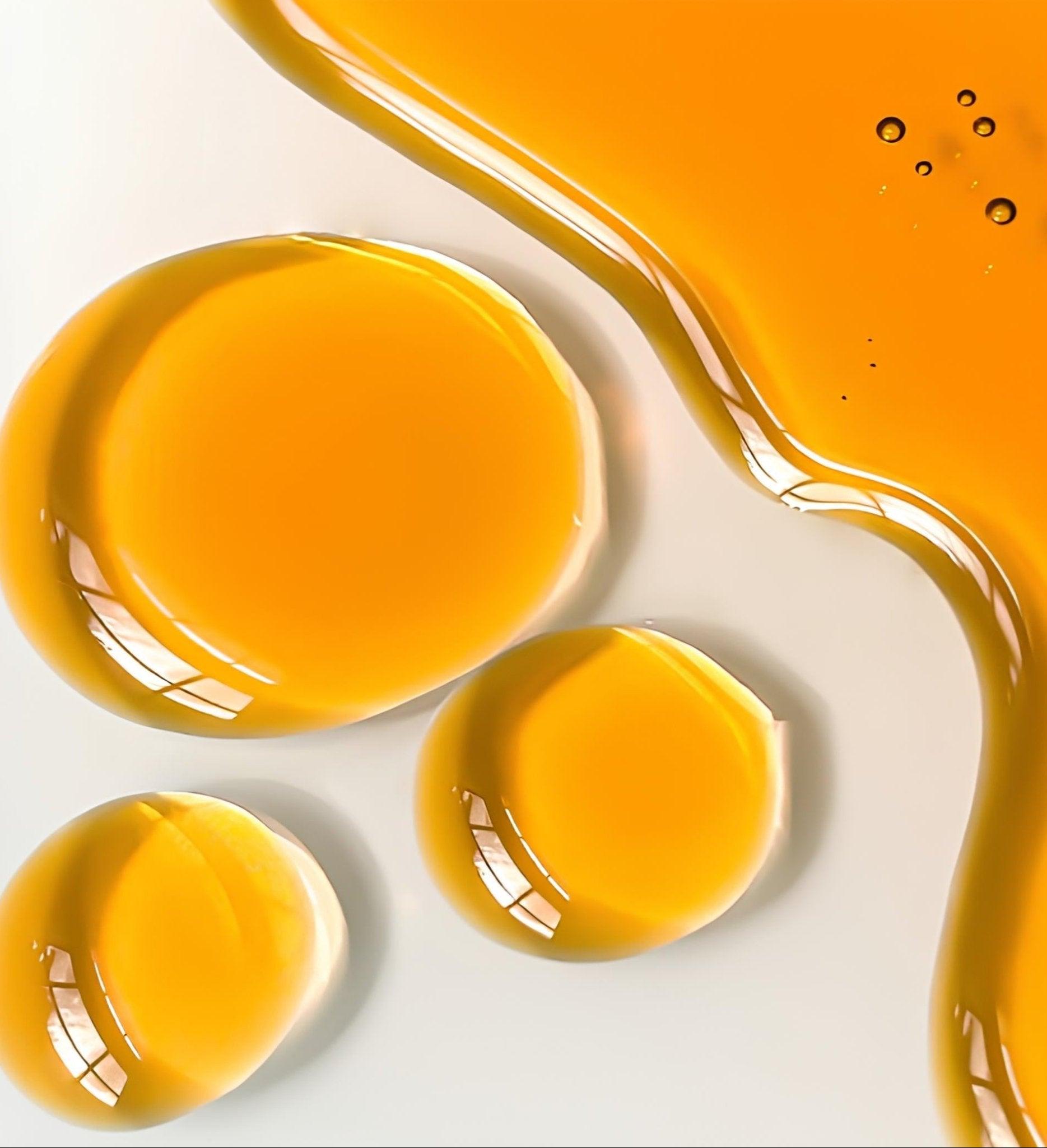 Eclat Soin Multi-Purpose Facial Oil shown in droplets on a smooth surface